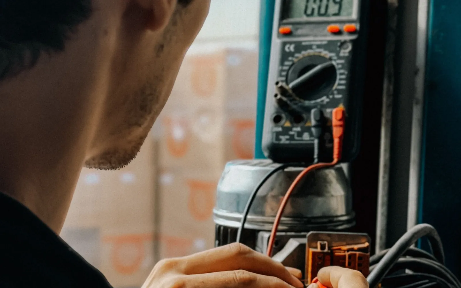Electrician reading a handheld multimeter during equipment testing.