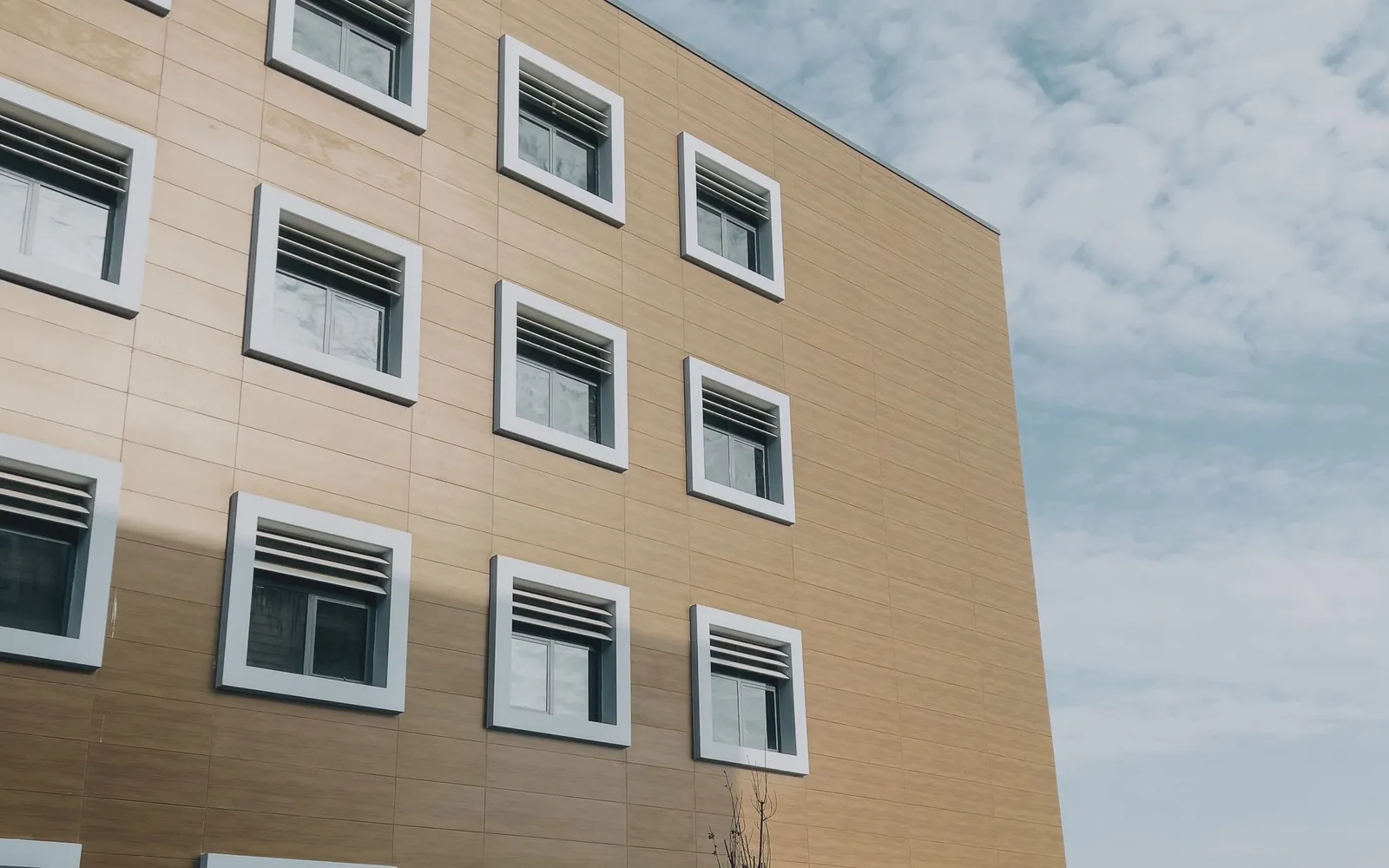Modern healthcare building exterior with rows of windows and an open forecourt.