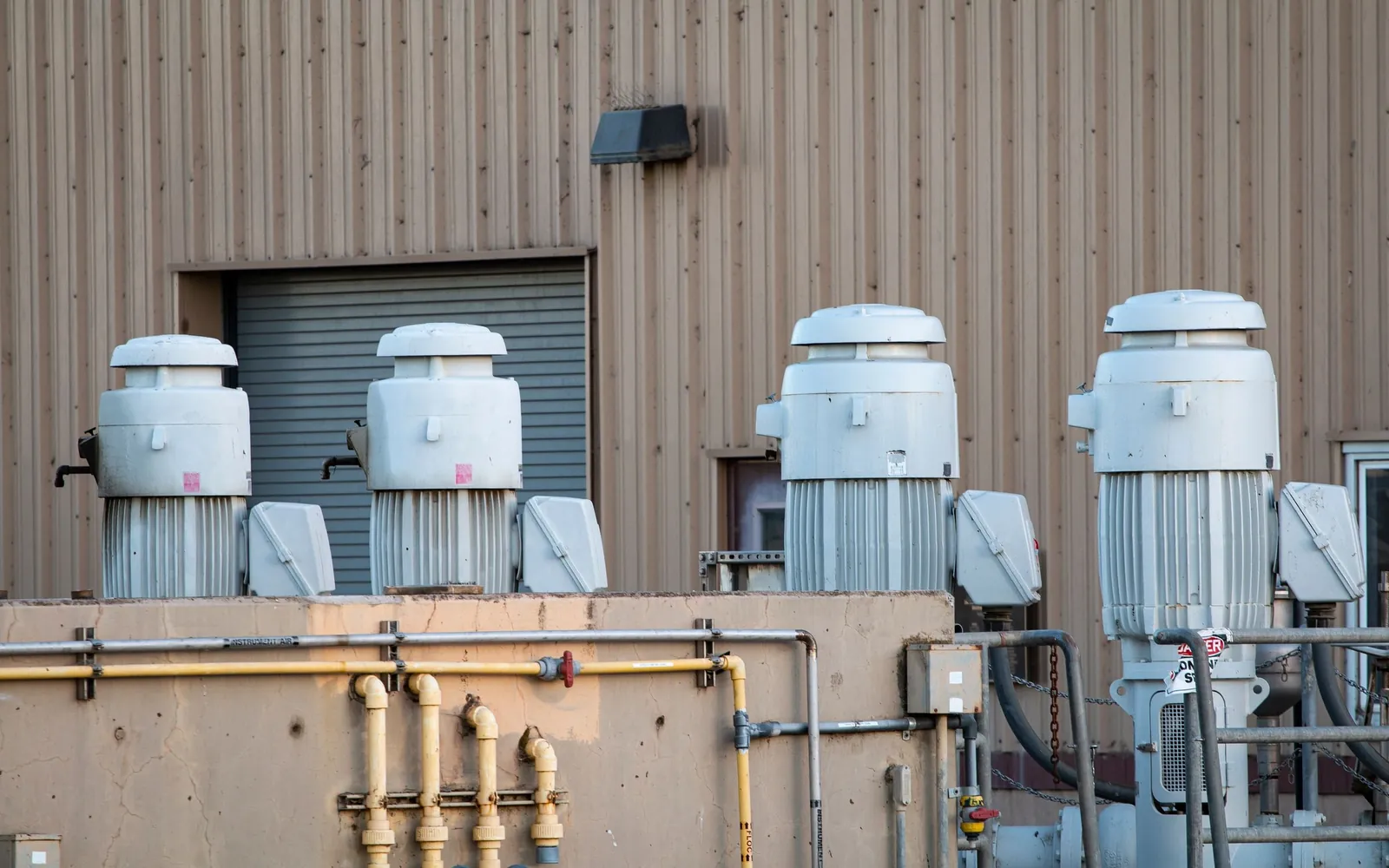 Industrial facility exterior with large motors, piping, and process equipment.