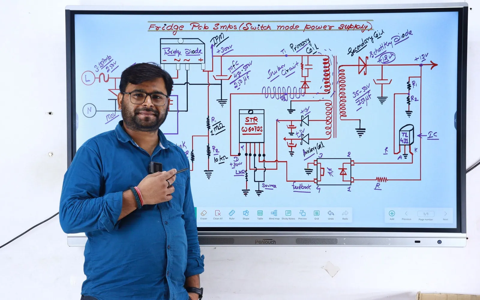 Adult instructor explaining an electronics power-supply circuit diagram on a classroom display.