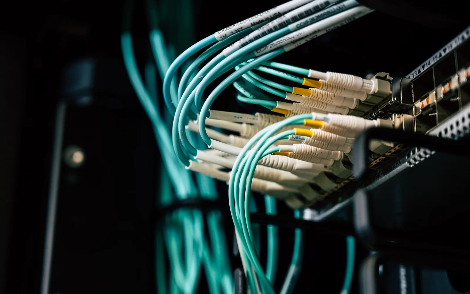 Technician connecting network cables in an equipment rack.