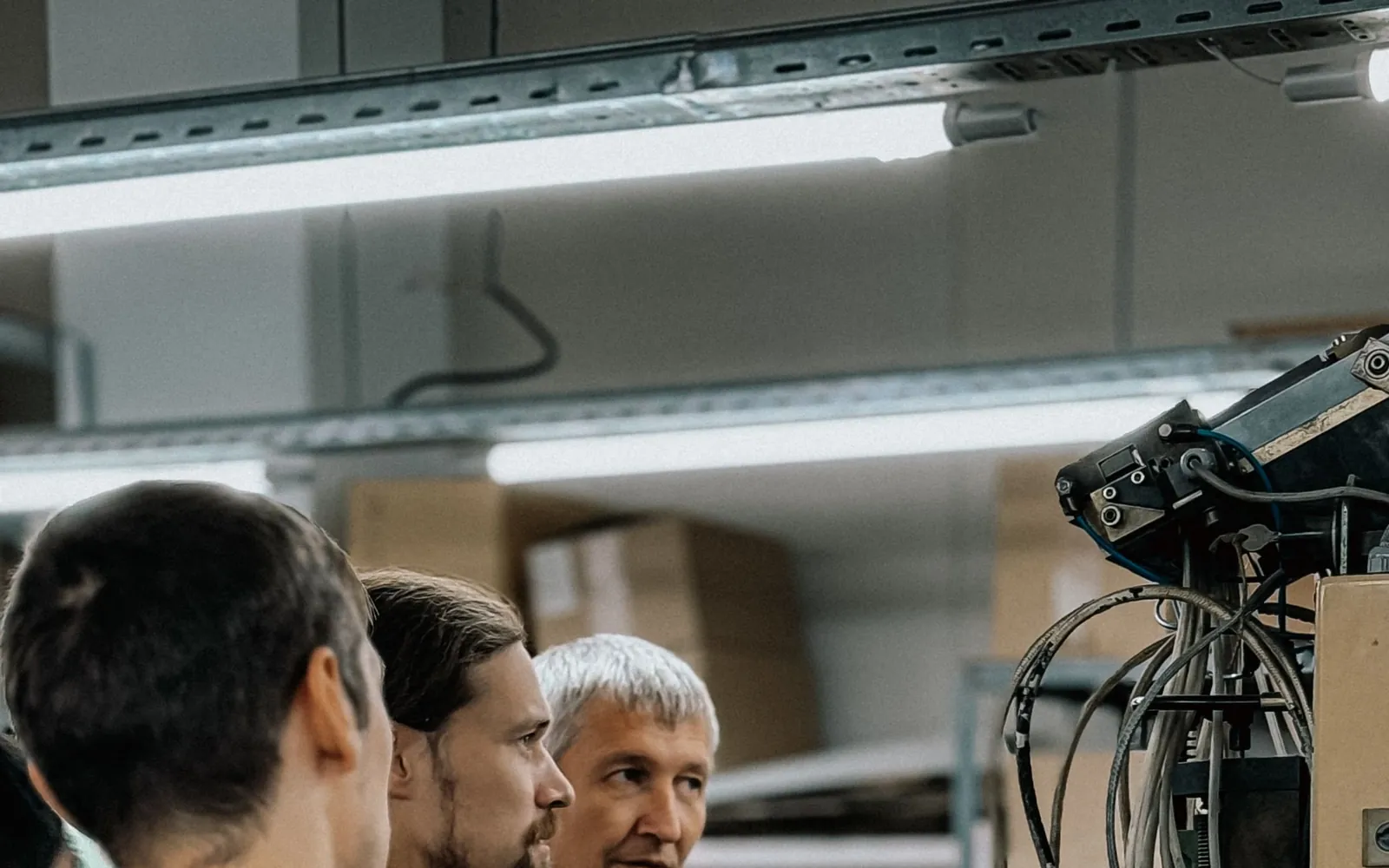 Three technical workers discussing equipment in an industrial work area.